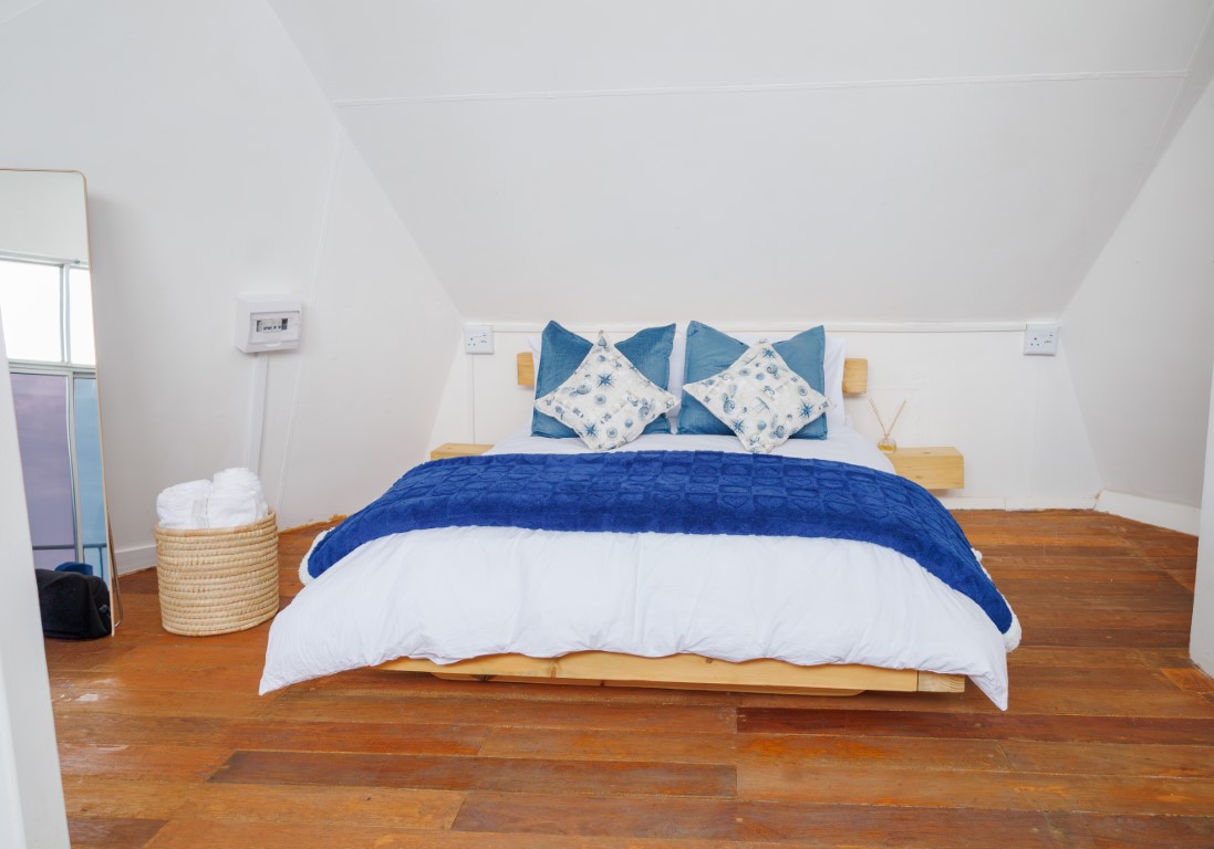 Real Binge bedroom with white bedding, blue cushions and wooden floors